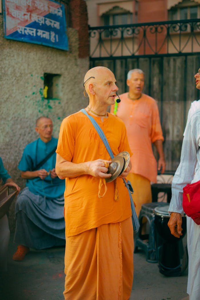 Group of musicians performing on the street in orange traditional attire, New Delhi.